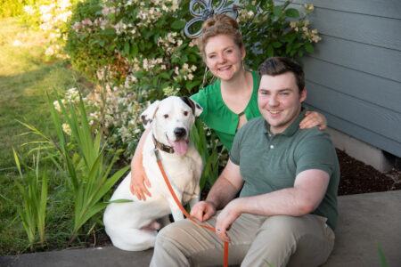 man woman and dog in front of house
